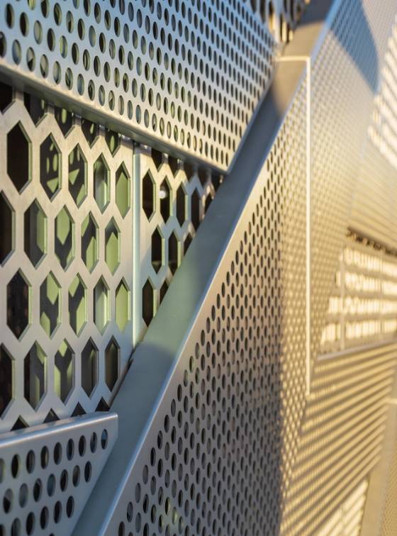 The building facade is made of hexagonal perforated metal.